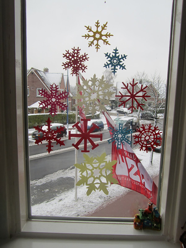 kerstboom op raam papieren sneeuwvlokken