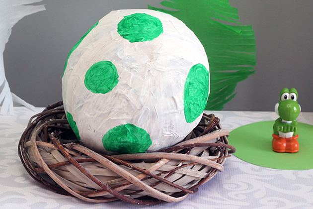 Dit Yoshi-ei van papier mache is heel gemakkelijk te maken. Wat je nodig hebt: een ballon, krantenpapier (repen 3 cm breed), water (2 delen), bloem (1 deel) en witte en groene verf. De hele ballon volplakken, maar bij het tuutje een gat openhouden. Een paar uur laten drogen (eventueel met behulp van een föhn) en dan nog een laag toevoegen. Nachtje laten drogen en de volgende dag ballon lek prikken en het ei twee maal met witte verf beschilderen. Eenmaal droog de groene stippen er op schilderen. Krans van de Action als nest. Natuurlijk ook erg leuk als pinata! 