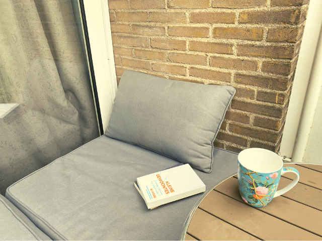 Foto van een rustige leesplek voor een moeder, met een zelfhulpboek en kopje thee.