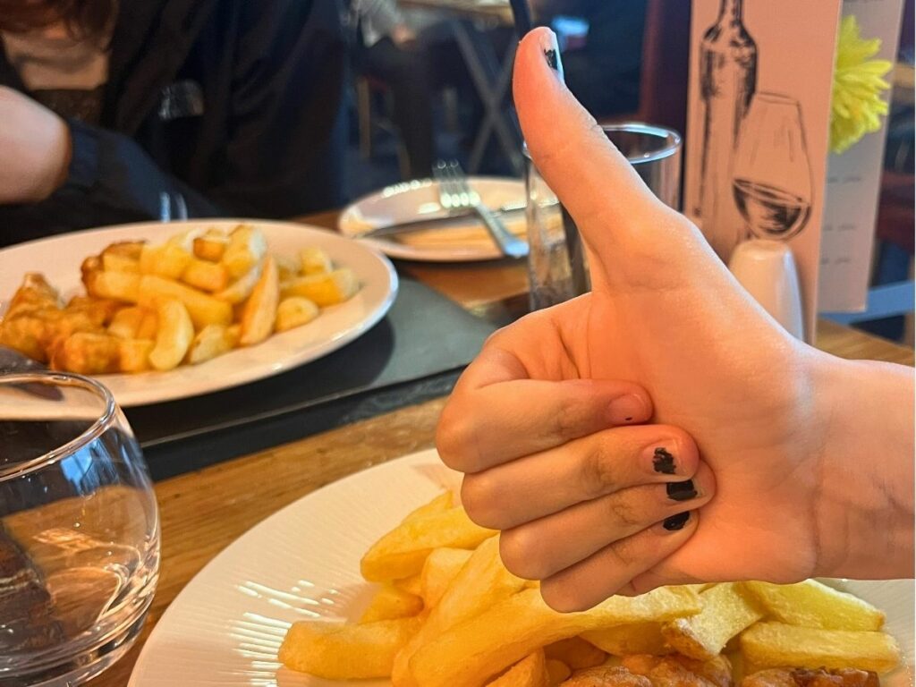 Kind steekt duim op in restaurant aan tafel bij het eten